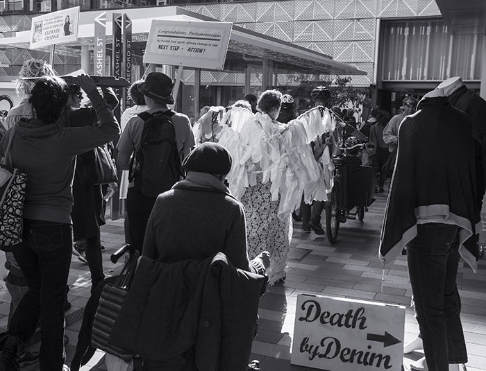 black and white photograph of a group of protesters in front of buildings and shops