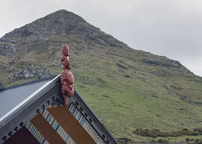 red aboriginal carving sculpture on a rooftop in front of a mountain 