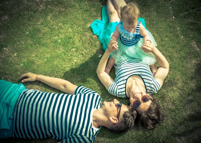 A shot of mom, dad and the little baby lying on grass