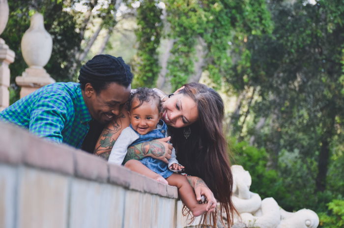 A family of three posing by a wall