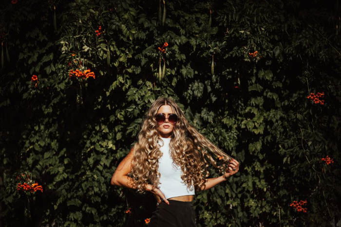 A fashion model posing in front of a bush 