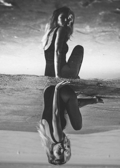 Creative monotone portrait of a female photography model posing outdoors on a beach - fashion photography composition