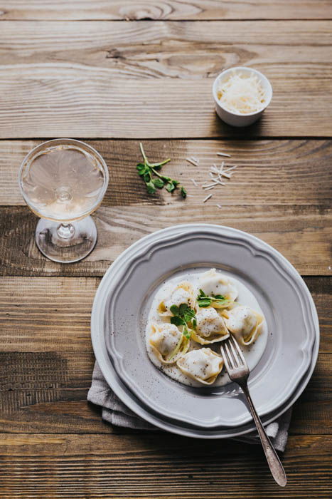 Overhead of fresh tortellini with cream sauce in triangle composition