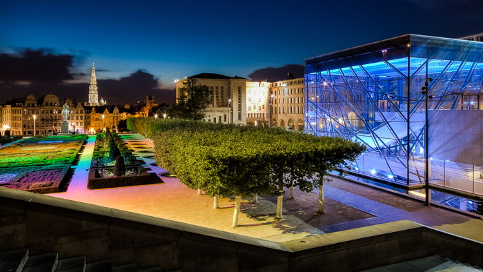 view of the outside of Mons des Arts with bright colored lights on the garden and buildings