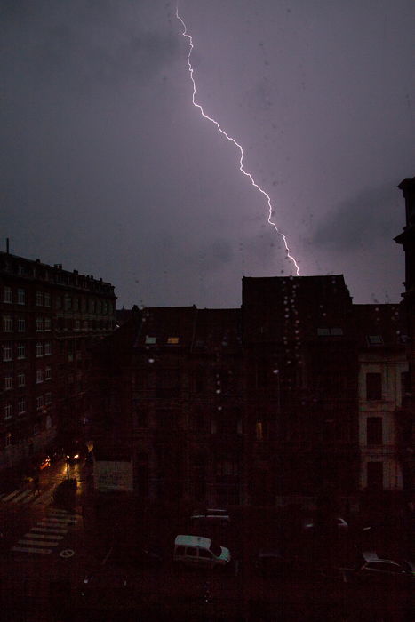 a bolt of lighting striking behind a dark and gloomy Brussels cityscape