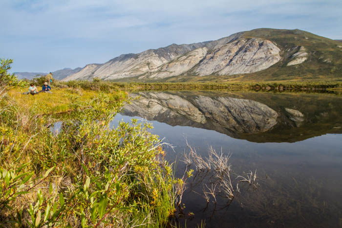 photographing beside a lake in Gates of the Arctic National Park, Alaska on a very bright day, the reflections on the pond mirroring the mountains.