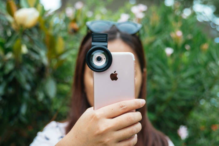 girl taking a photo with an iphone with a clip on macro lens