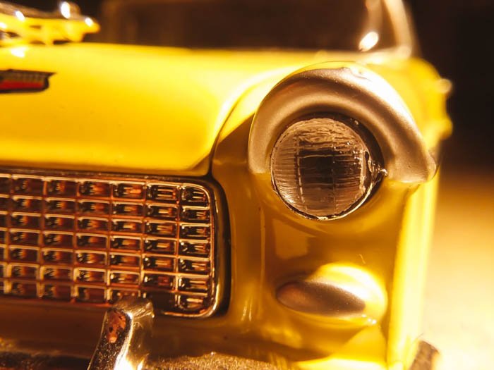 close up iphone photo of yellow car headlight