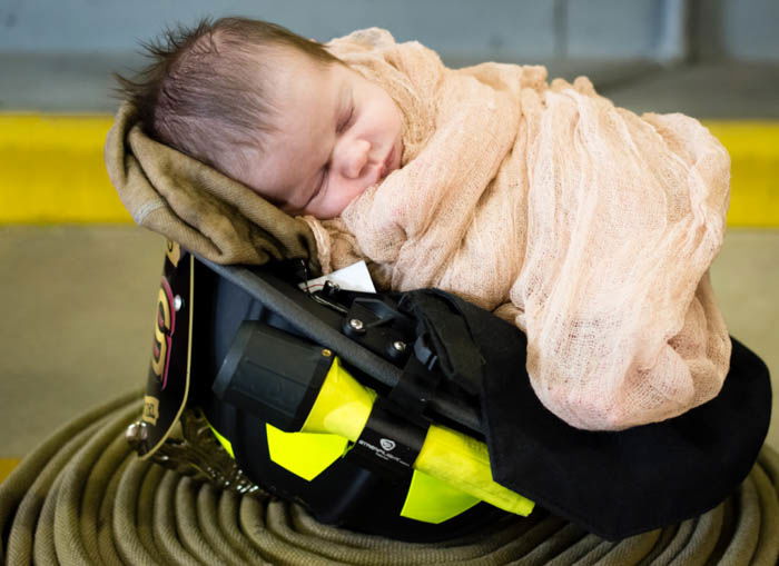 newborn baby in a cute helmet prop