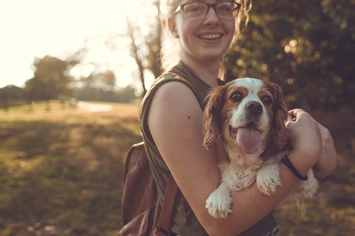 portrait of a young woman with a King Charles spaniel in her arms
