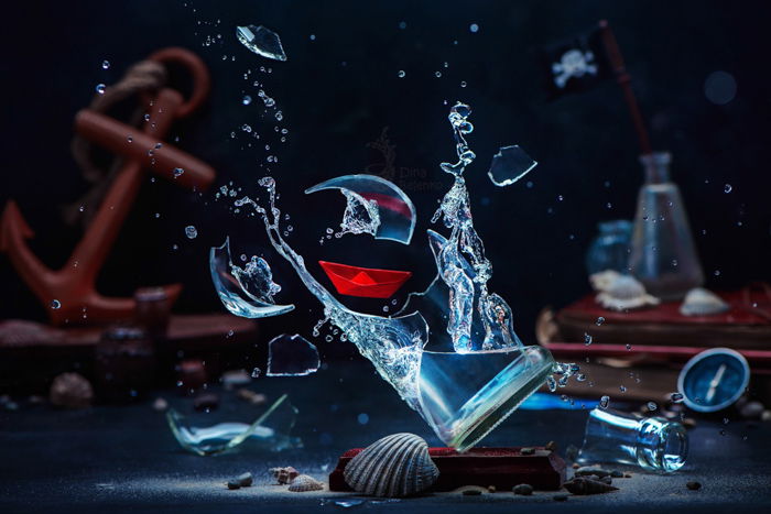 Still life of a glass of water breaking surrounded by sea themed objects