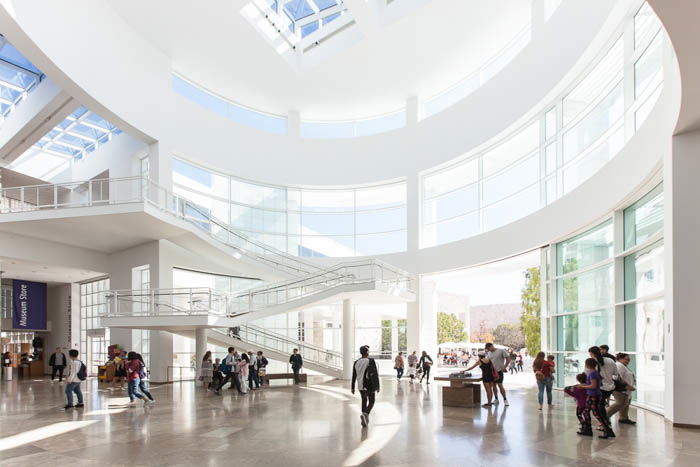 photo of a white spacious building from the inside with people standing and walking around the ground floor