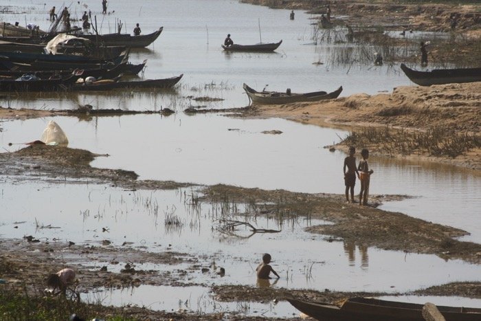 Travel photography showing people living in extreme poverty. River scene with wooden fishing boats and people