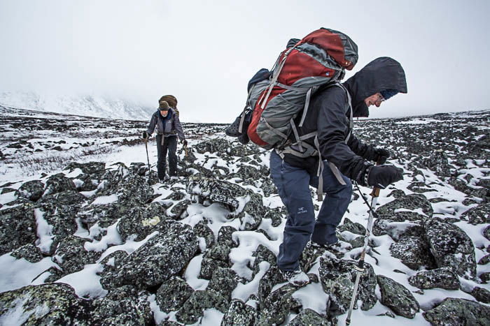 an image of two people wearing backpacks hiking in snow covered mountains