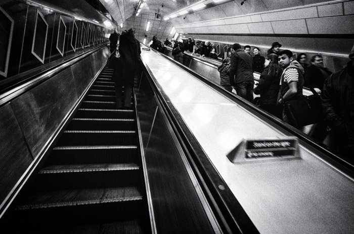 Black and white image of people on a metro station elevator 
