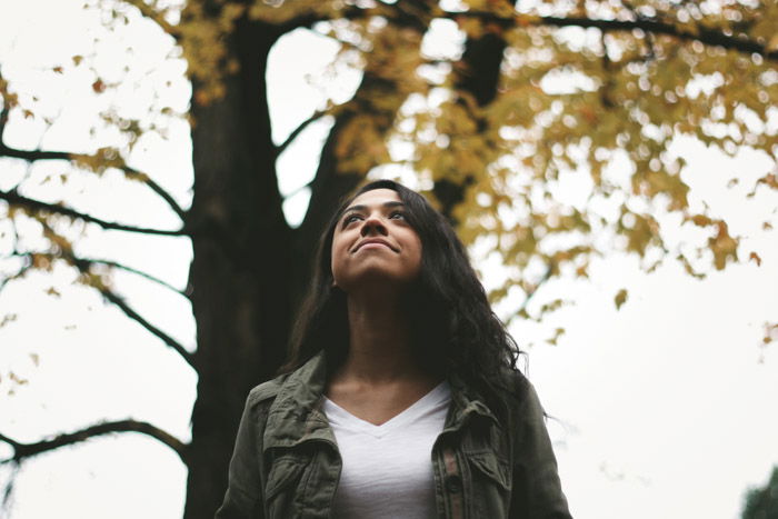 Low angle composition of a woman in front of trees