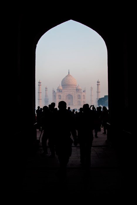 A crowd walking towards the Taj mahal framed by an archway