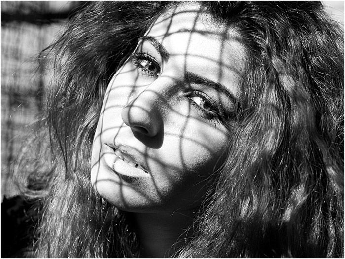 A greyscale portrait of a female model with dappled lighting on her face