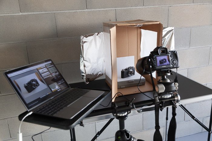 DIY lightbox with camera on a tripod and laptop placed next to it