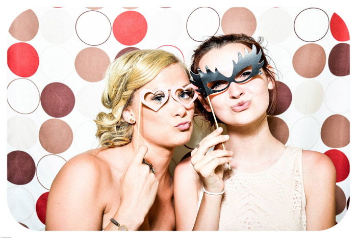 two young girls posing with masks in front of a colorful photo background