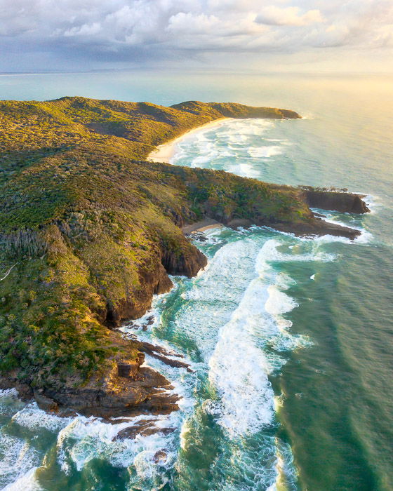 side-lighting drone photography of a rugged coastline and seascape on a bright cloudy day