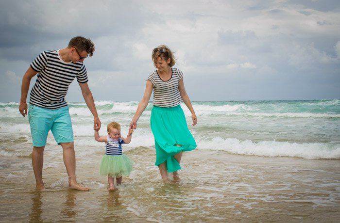 一对夫妇和小孩在海滩上散步的家庭照片