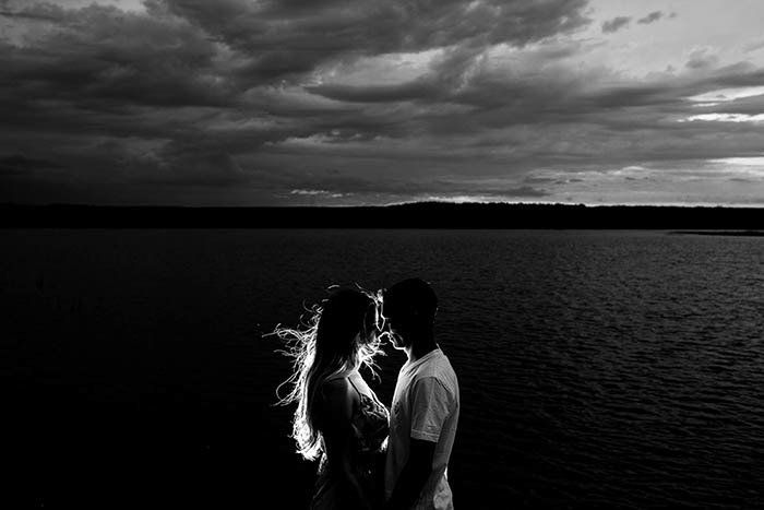 Black and white portrait of a couple kissing by the sea