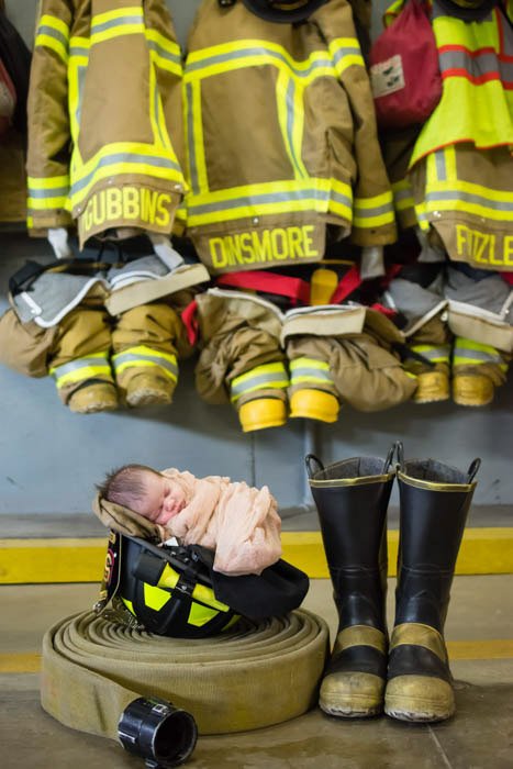 a newborn baby posed with fireman paraphernalia 