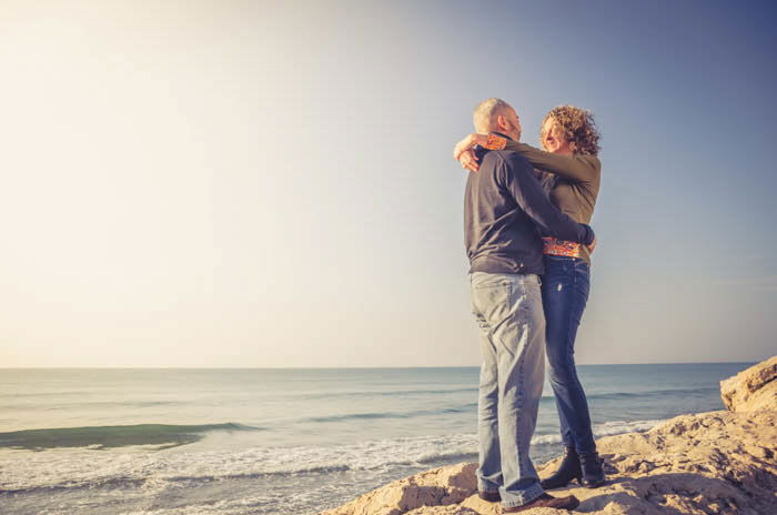 A couple posing on rocks by the beach