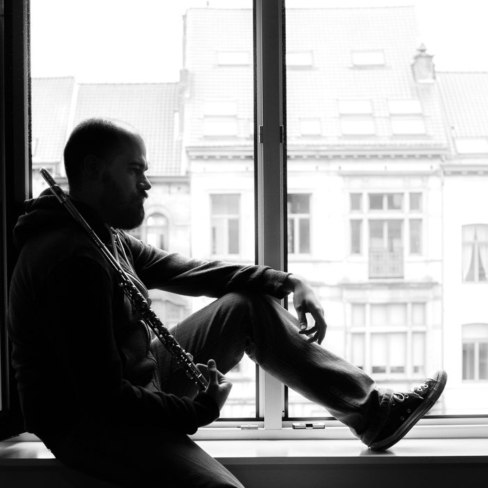 black and white portrait of man sitting in a window frame