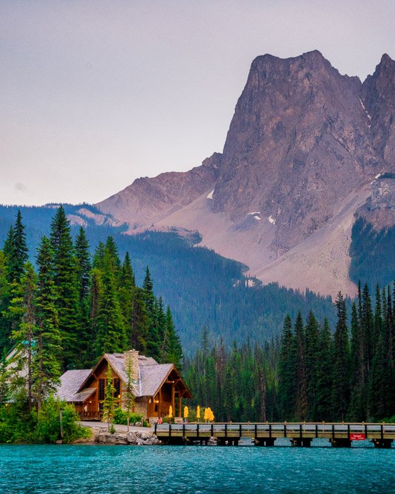 Stunning landscape photo composition of mountains above a small house, pier and lake