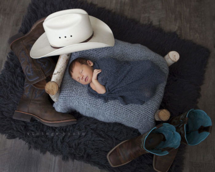 A newborn sleeping surrounded by props