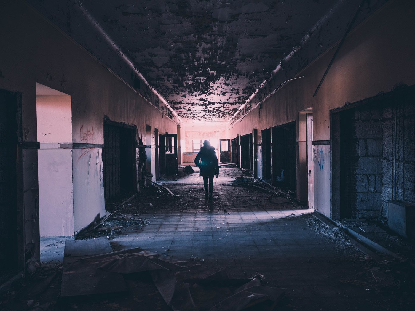 A person walking in an abandoned building hallway for urbex photography