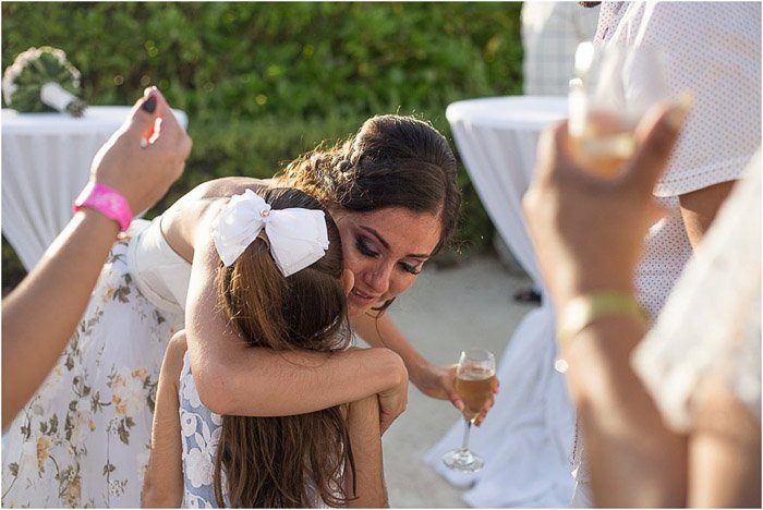 Bride hugging young flowergirl amidst guests clapping. Amateur wedding photography.