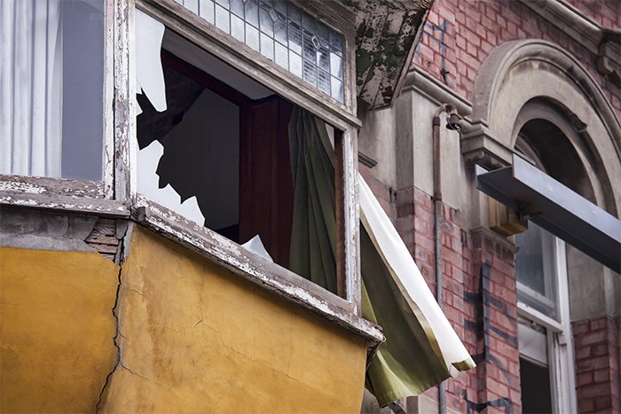 建筑立面的特写显示了2个窗台，其中一个玻璃破碎了。新西兰基督城地震后的建筑照片。