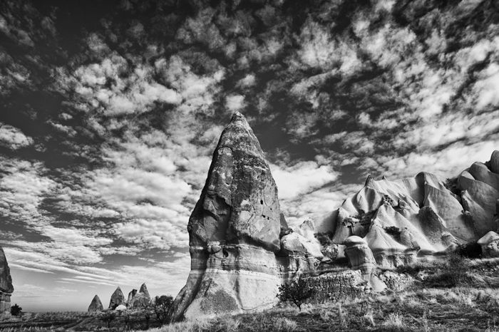 Black and white travel photography of large rocks beneath a scraggy cloudy sky