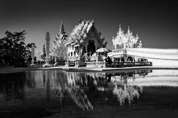 Black and white travel photograph of the White Temple in Chiang Rai, Thailand, the building reflected in the water below