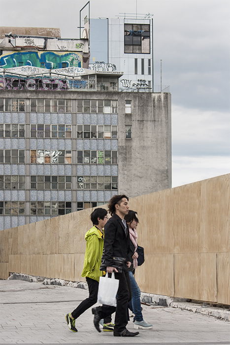 Street photo of three people walking past an apartment block. Creative street photography