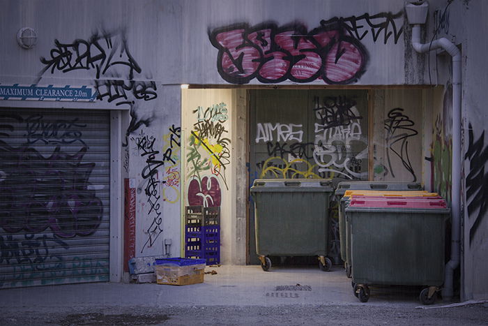 Creative street photography of buildings with graffiti and rubbish bins.