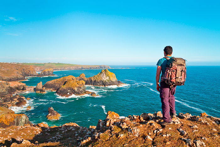 A male backpacker standing on rocky cliffs overlooking a fantastic seascape