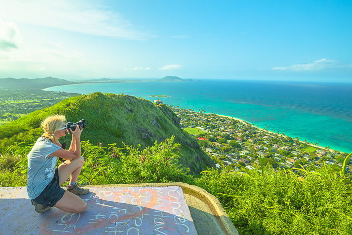 A female photographer taking pictures of a stunning landscape below 