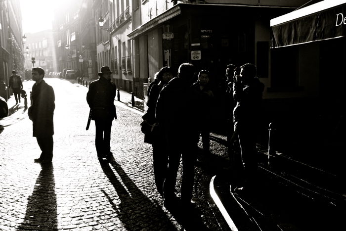 Black and white street photography of a group of people talking.