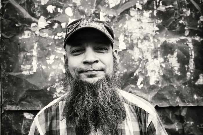 Black and white portrait of a man with cap and beard. 