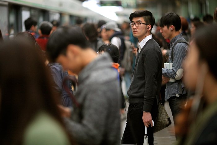 Fotografía callejera de una multitud de personas esperando un tren.