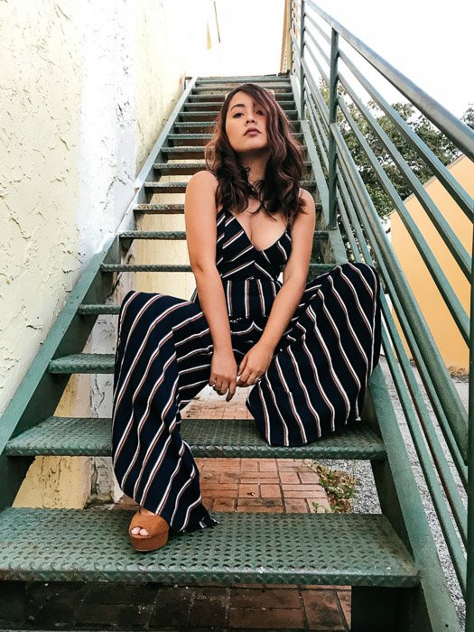 Portrait of a girl in a black and white striped outfit sitting on green steps outdoors - Smartphone fashion photography shoot