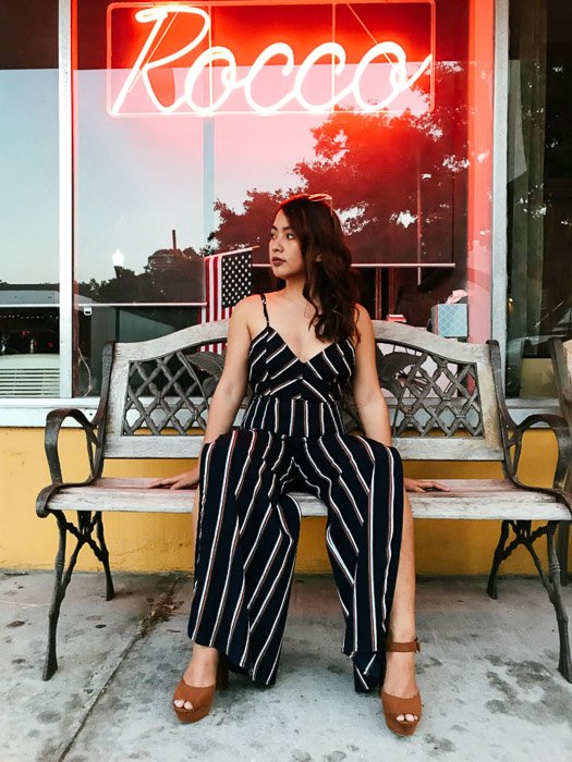Portrait of a girl in a black and white striped outfit sitting on a wooden bench outside a cafe - Smartphone fashion photography shoot