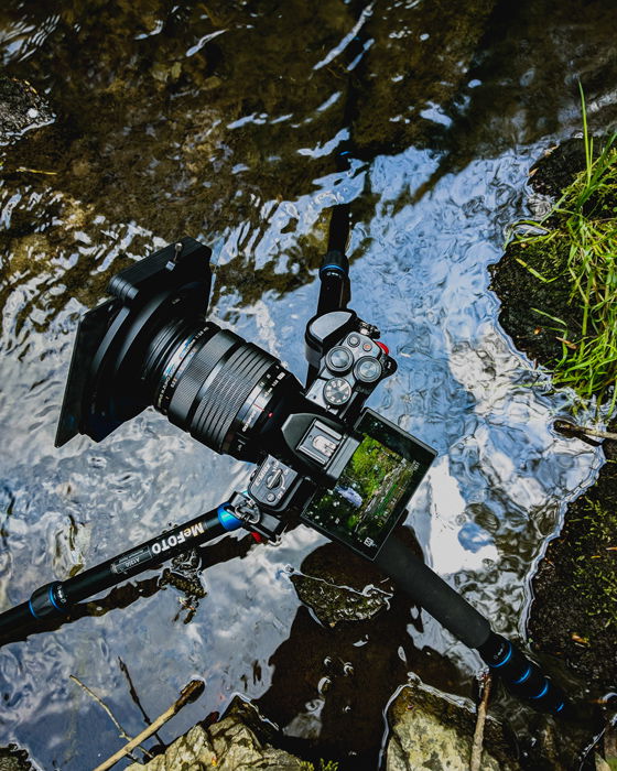 Overhead image of a tripod in a water stream set up to photograph waterfalls