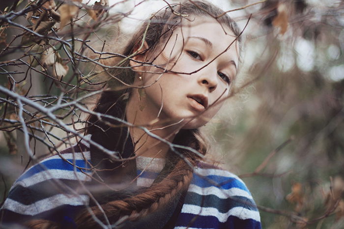 Portrait of a dark haired girl with a blurry forest background. 