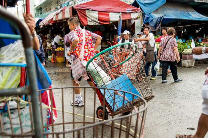 Documentary photography portrait of a man pulling steel carts at Muang Mai Market, Chiang Mai, Thailand.