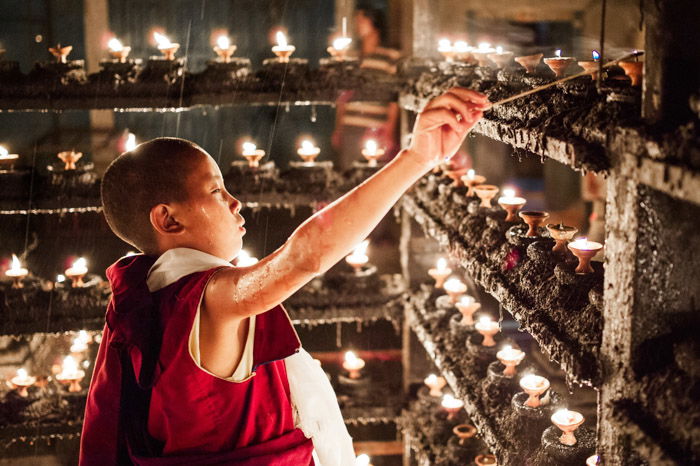 Martin Edstrom travel photography of a young boy lighting a candle. Famous photographers to follow online